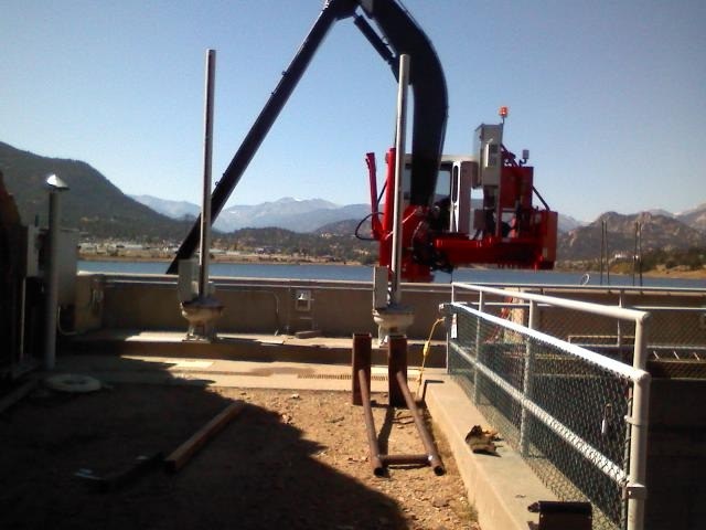 Articulating boom rack cleaner installed at Olympus Dam with the Colorado mountains behind it
